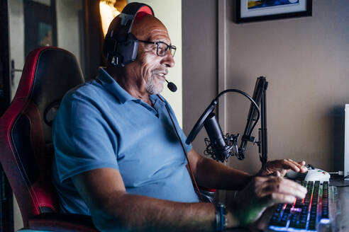 Älterer Mann beim Online-Streaming, während er zu Hause ein Videospiel spielt - MEUF03414