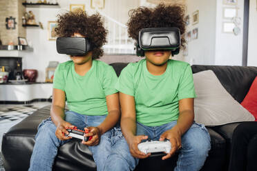 Twin brothers playing game wearing Virtual reality glasses at home - MEUF03416