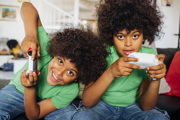 Aufgeregte Zwillingsbrüder spielen zu Hause ein Videospiel - MEUF03434