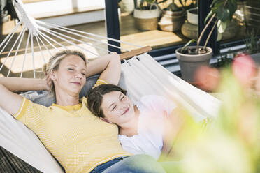 Woman and girl napping together in hammock - UUF23837