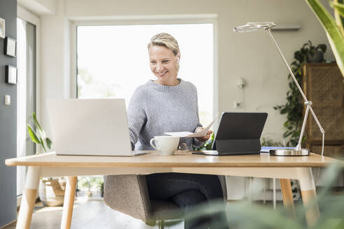 Lächelnde Freiberuflerin bei der Arbeit im Home Office - UUF23859