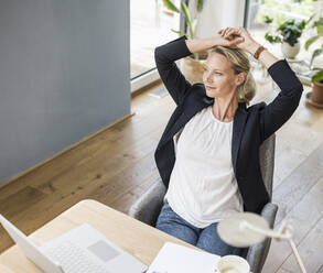 Thoughtful businesswoman looking away while sitting at office - UUF23878