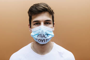 Man wearing protective face mask with text in front of orange wall - XLGF02101