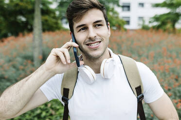Smiling young man looking away while talking on smart phone - XLGF02112
