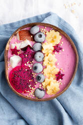 From above of power bowl full of tasty smoothie near ripe banana and dragon fruit slices with blueberries for breakfast - ADSF25374