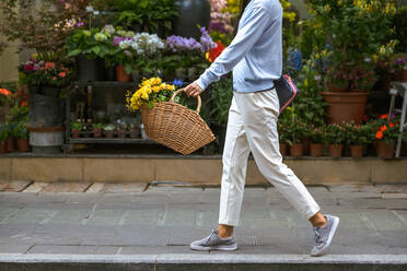 Side view of girl's body carrying a flower basket while she walks - ADSF25390