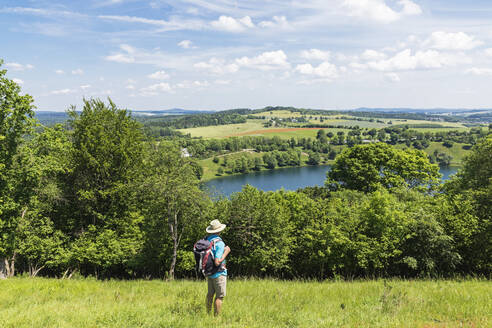 Senior hiker admiring landscape surrounding Weinfelder Maar lake - GWF07076