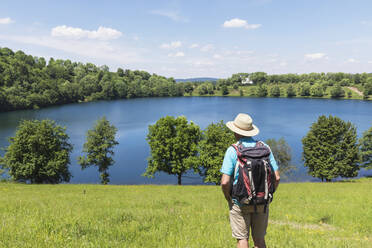 Senior hiker admiring view of Weinfelder Maar lake - GWF07082