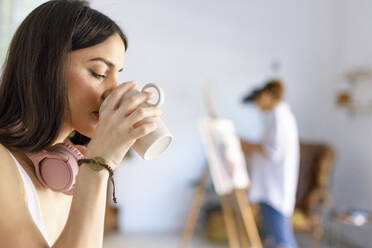 Woman drinking coffee in artist's studio - IFRF00897