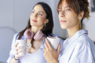 Contemplating female creative colleagues looking away holding mugs in studio - IFRF00921