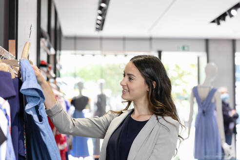 Young woman looking at dress while shopping in boutique - EIF01531