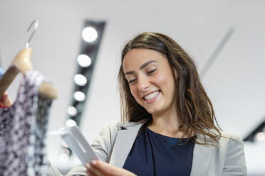 Lächelnde Frau mit Blick auf das Preisschild in einer Boutique - EIF01538