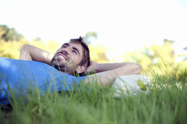 Young man contemplating while lying on grass at park - AJOF01493