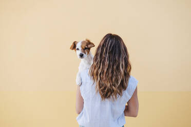 Mittlere erwachsene Frau mit Hund vor einer Mauer - EBBF04181