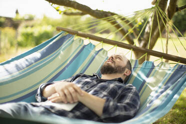 Gelassener Mann entspannt in sonniger Sommerhängematte - CAIF30850