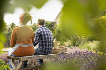 Ehepaar macht eine Pause von der Gartenarbeit im sonnigen Sommergarten - CAIF30866