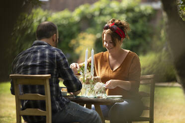 Happy couple enjoying cake at table in summer garden - CAIF30878
