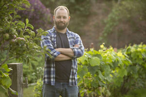 Porträt selbstbewusster gut aussehender Mann mit Bart im Garten - CAIF30881