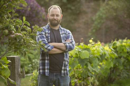 Portrait confident handsome man with beard in garden - CAIF30881