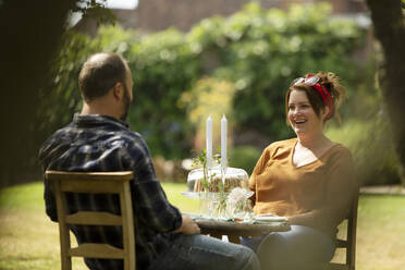 Glückliches Paar genießt Kuchen am Sommertisch im Garten - CAIF30888