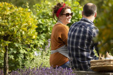 Ehepaar macht eine Pause von der Gartenarbeit im sonnigen Sommergarten - CAIF30889