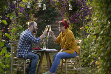 Happy couple toasting champagne in idyllic summer garden - CAIF30927