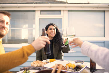 Glückliche Freunde stoßen bei Wein und Bier auf ein Mittagessen mit Meeresfrüchten auf der Terrasse an - CAIF30950