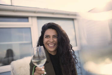 Happy carefree woman enjoying white wine on patio - CAIF30959