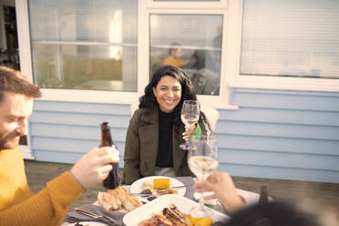Glückliche Frau genießt Wein und Meeresfrüchte mit Freunden auf dem Terrassentisch - CAIF30968