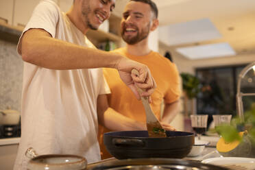 Glückliches schwules männliches Paar beim Kochen in der Küche - CAIF31024
