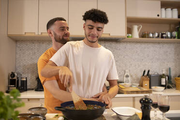 Liebevolles schwules männliches Paar beim Kochen in der Küche - CAIF31026