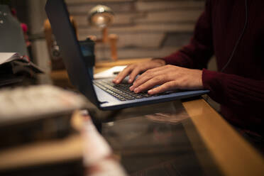 Nahaufnahme eines jungen Mannes bei der Arbeit an einem Laptop auf einem Schreibtisch im Büro zu Hause - CAIF31042