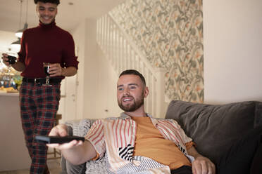 Schwules männliches Paar mit Wein beim Fernsehen zu Hause - CAIF31067