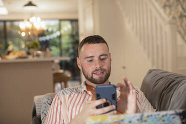 Young man using smart phone on sofa - CAIF31079