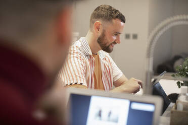 Happy young man working from home at digital tablet - CAIF31089