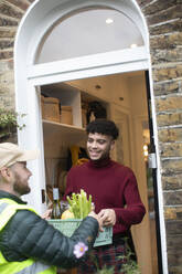 Man receiving grocery delivery from delivery man at front door - CAIF31112