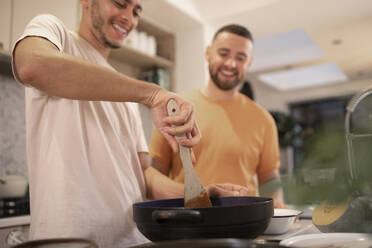 Glückliches schwules männliches Paar beim Kochen in der Küche - CAIF31140
