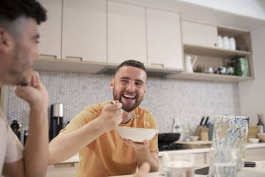 Glückliches schwules männliches Paar beim Essen in der Küche - CAIF31142