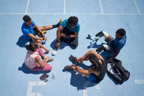 Junge Sportler im Gespräch auf der sonnigen blauen Sportbahn - CAIF31160