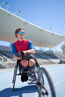 Porträt eines selbstbewussten männlichen Rollstuhlsportlers auf einer sonnigen Sportstrecke - CAIF31166
