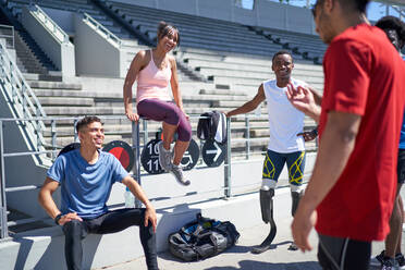 Junge Athletenfreunde unterhalten sich in einem sonnigen Sportstadion - CAIF31187