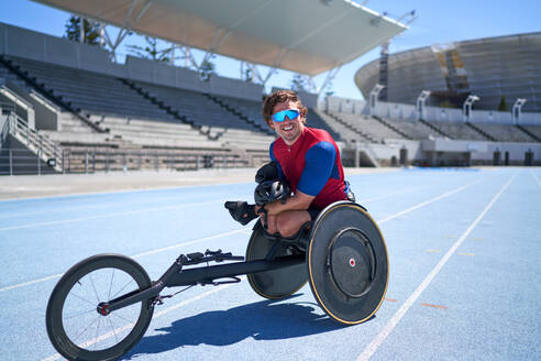 Portrait confident male wheelchair athlete on sunny blue sports track - CAIF31188