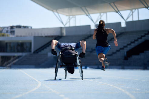 Wheelchair athlete training on sunny blue sports track - CAIF31207