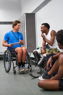 Rollstuhlfahrer und amputierte Sportler mit digitalem Tablet in der Umkleidekabine - CAIF31210