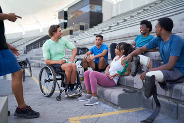Vielfältige junge Sportler im Gespräch auf der Stadiontribüne - CAIF31212