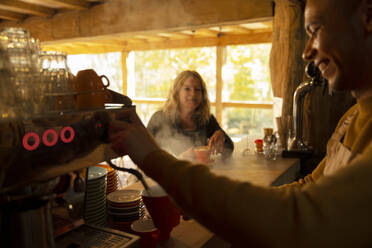 Barista bereitet Kaffee für Kunden an einer Espressomaschine in einem Café zu - CAIF31266
