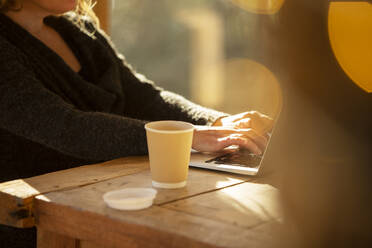 Woman with coffee working at laptop on cafe table - CAIF31270
