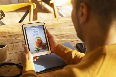 Männlicher Restaurantbesitzer, der sich die Liefer-Website auf einem digitalen Tablet ansieht - CAIF31282