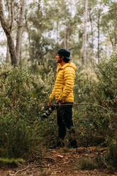 Side view of a photographer in a cap and yellow jacket on the mountain looking away - ADSF25570