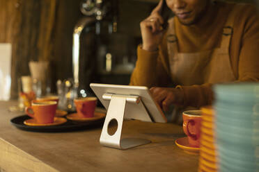 Männlicher Barista mit digitalem Tablet an der Kaffeetheke - CAIF31357